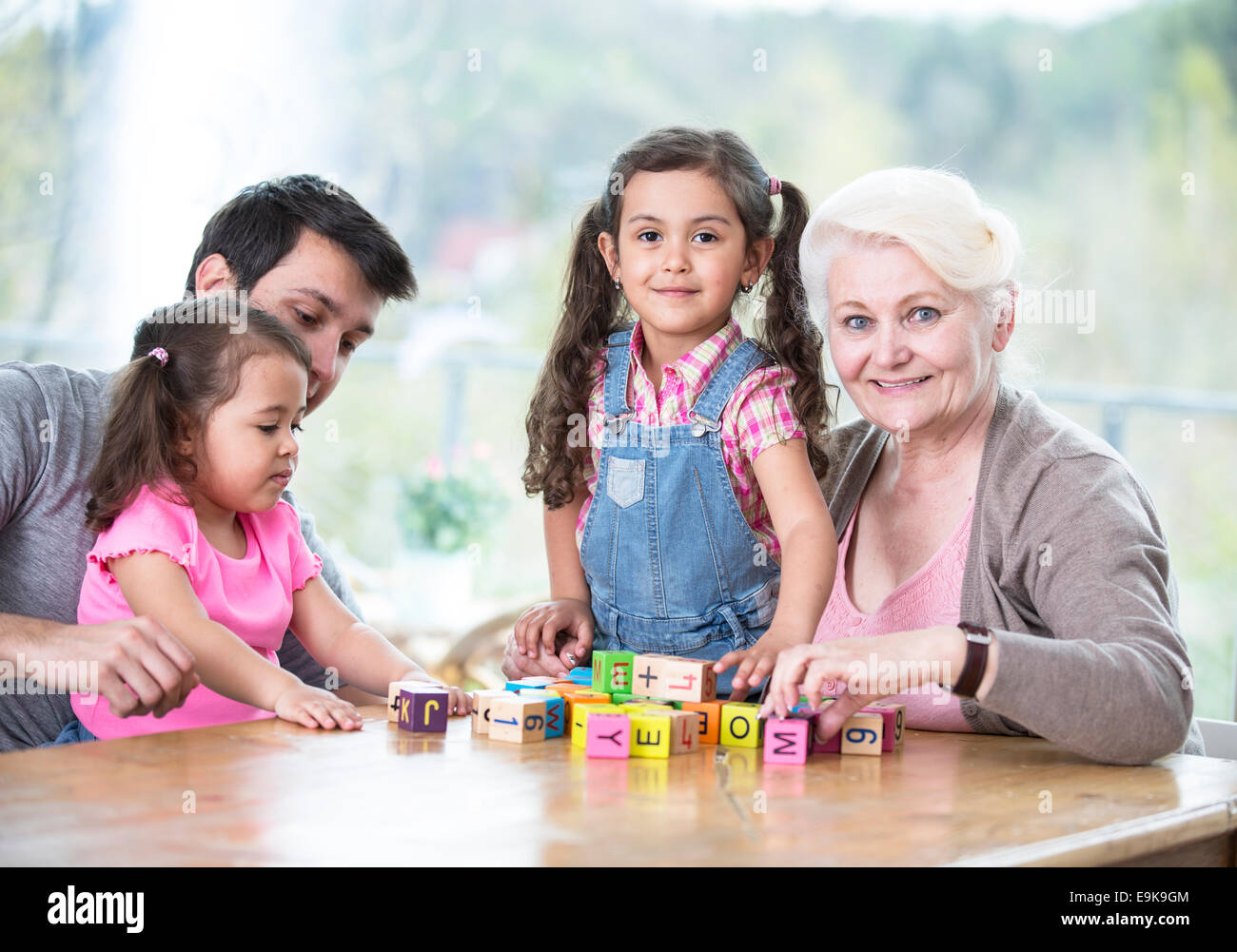 Felice tre generazioni la famiglia gioca con blocchi di alfabeto a casa Foto Stock