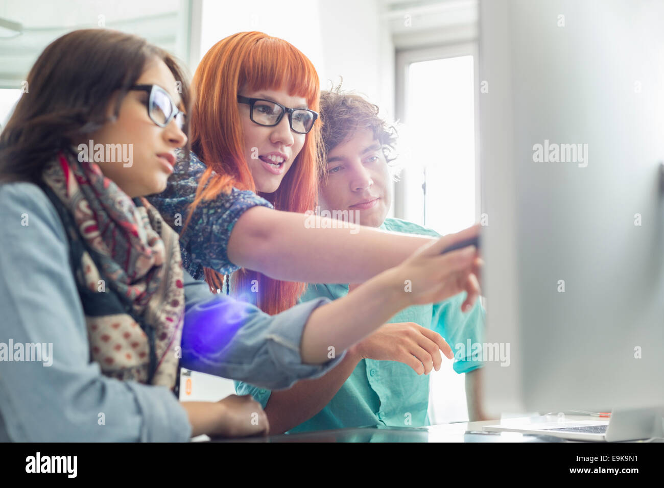 Colleghi di lavoro discutendo su computer in ufficio creativo Foto Stock