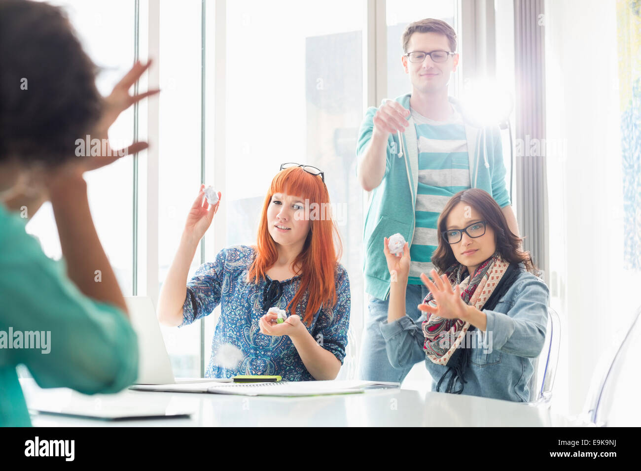 Arrabbiato gli imprenditori lanciando palle di carta su un collega in ufficio creativo Foto Stock