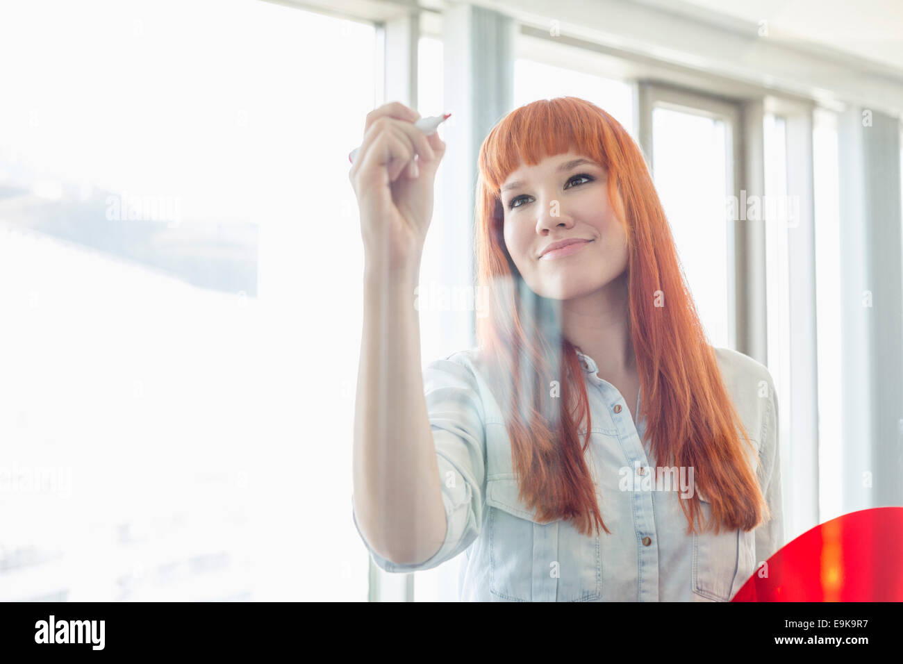 Imprenditrice creativa la scrittura sulla parete di vetro in office Foto Stock