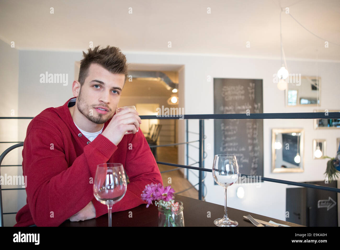 Ritratto di fiducioso giovane uomo di bere acqua dal vetro in cafe Foto Stock