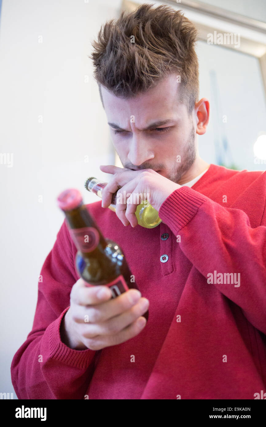 Giovane uomo la lettura di etichetta sulla bottiglia di birra in cafe Foto Stock