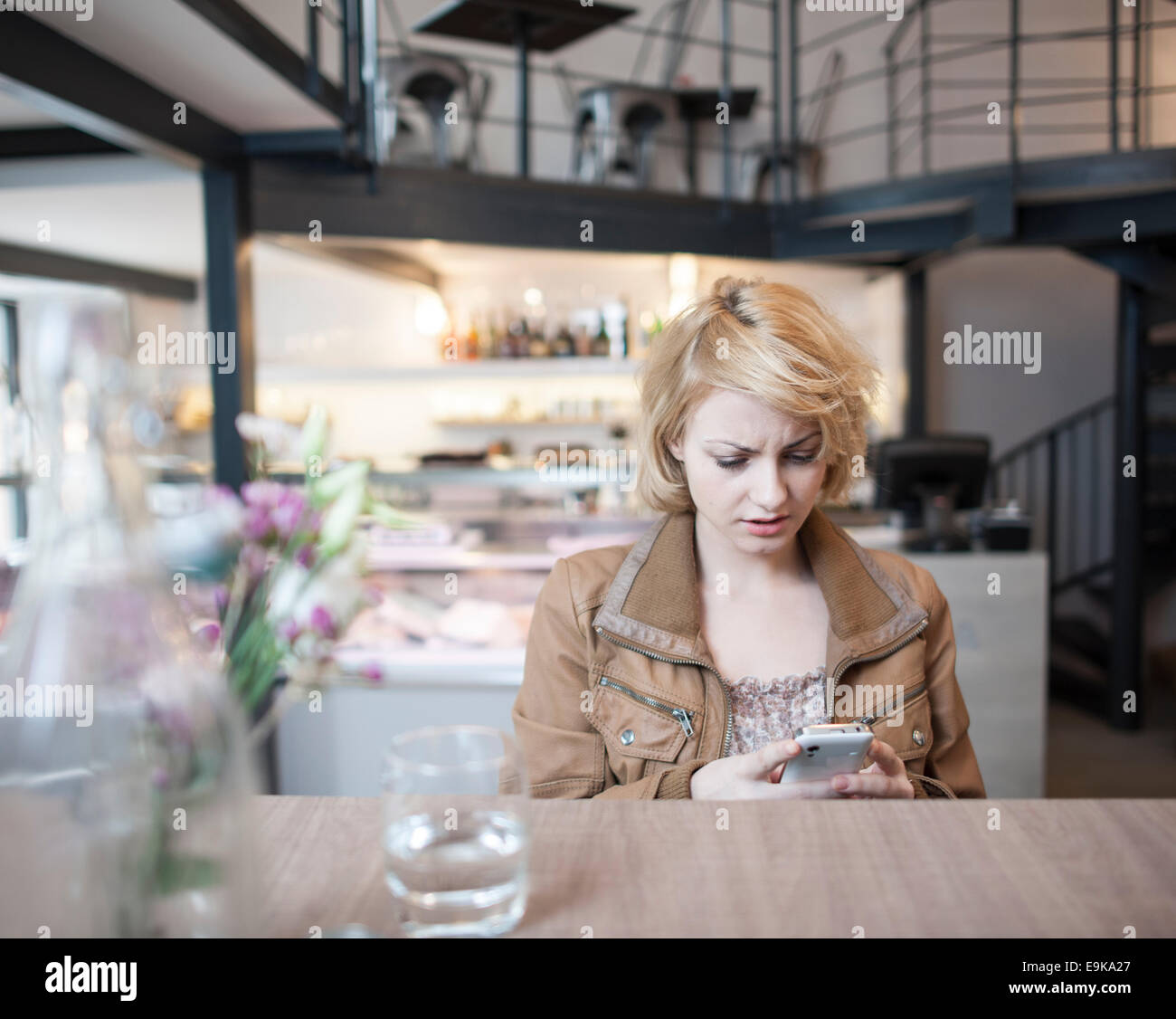 Preoccupato per il giovane donna la lettura di un messaggio di testo sul telefono cellulare in cafe Foto Stock