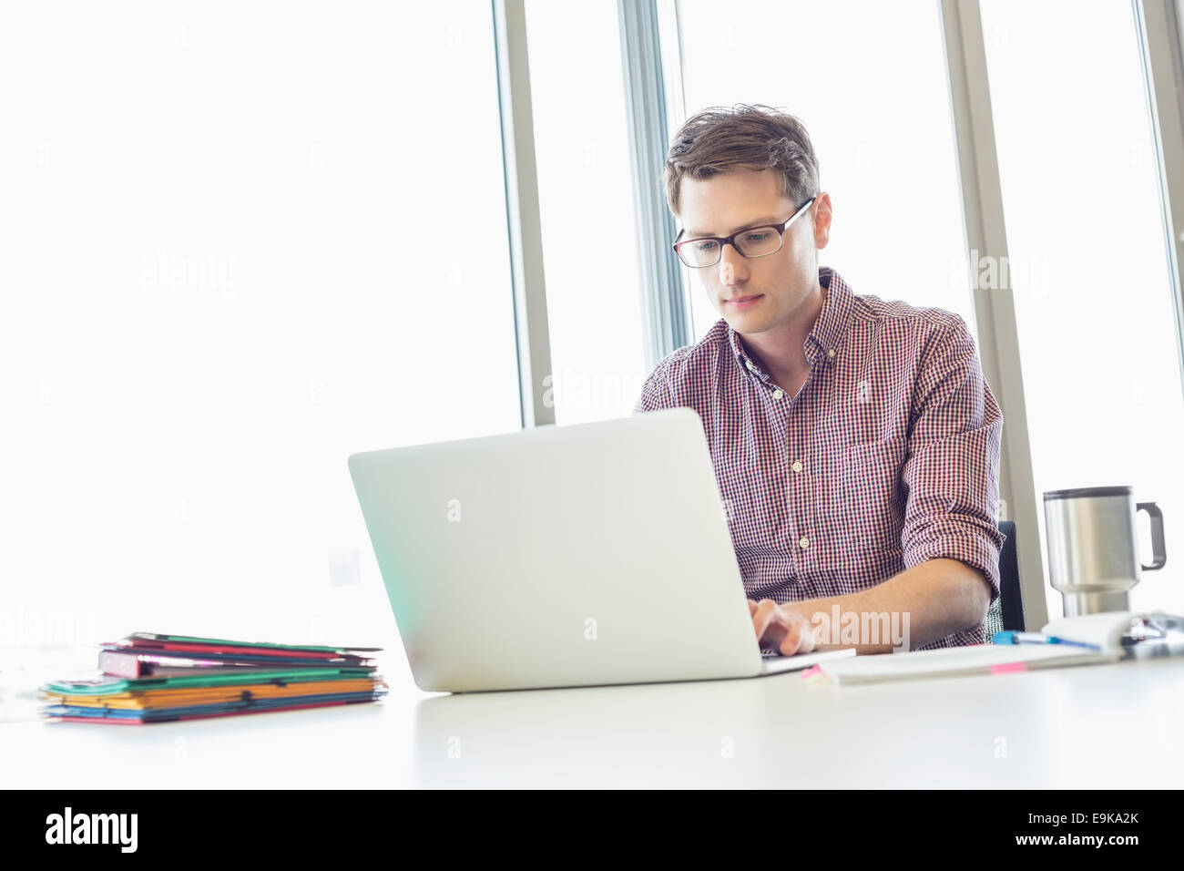 Mid-adulto imprenditore notebook di lavoro alla scrivania in ufficio creativo Foto Stock