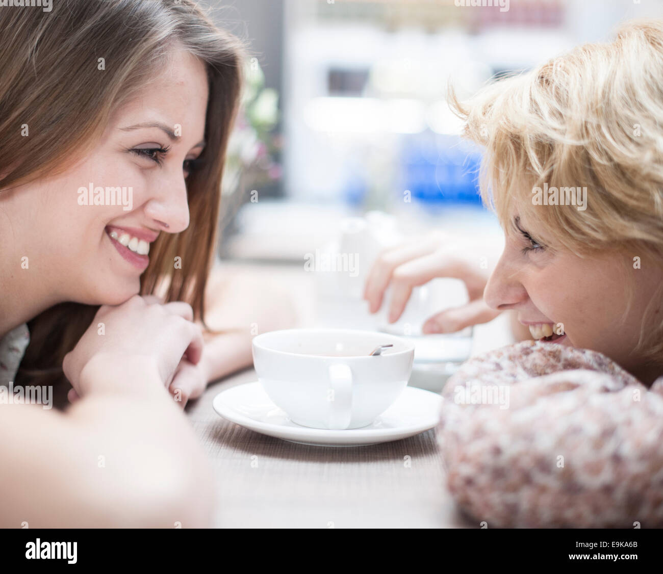 Vista laterale di sorridere giovani amici di sesso femminile guardando ogni altro in cafe Foto Stock