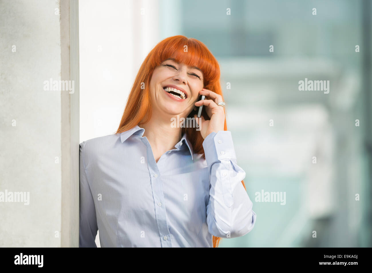 Allegro imprenditrice parlando al cellulare in ufficio Foto Stock