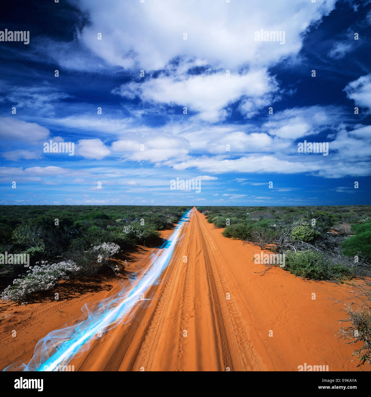 Blue Streak di luce su strada sterrata contro il cielo nuvoloso Foto Stock