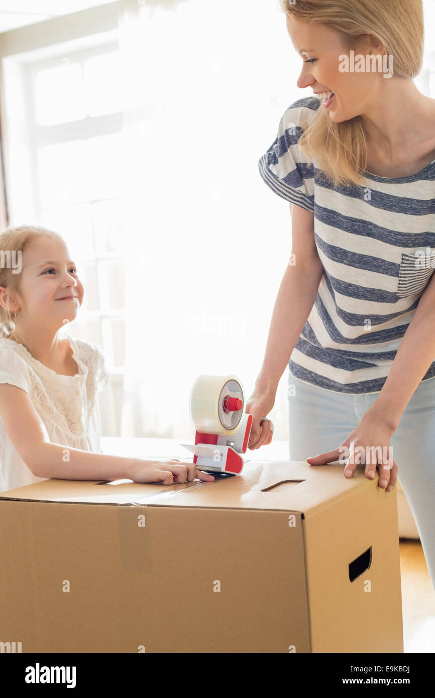 Madre e figlia guardando ogni altro mentre imballo scatola di cartone a casa Foto Stock