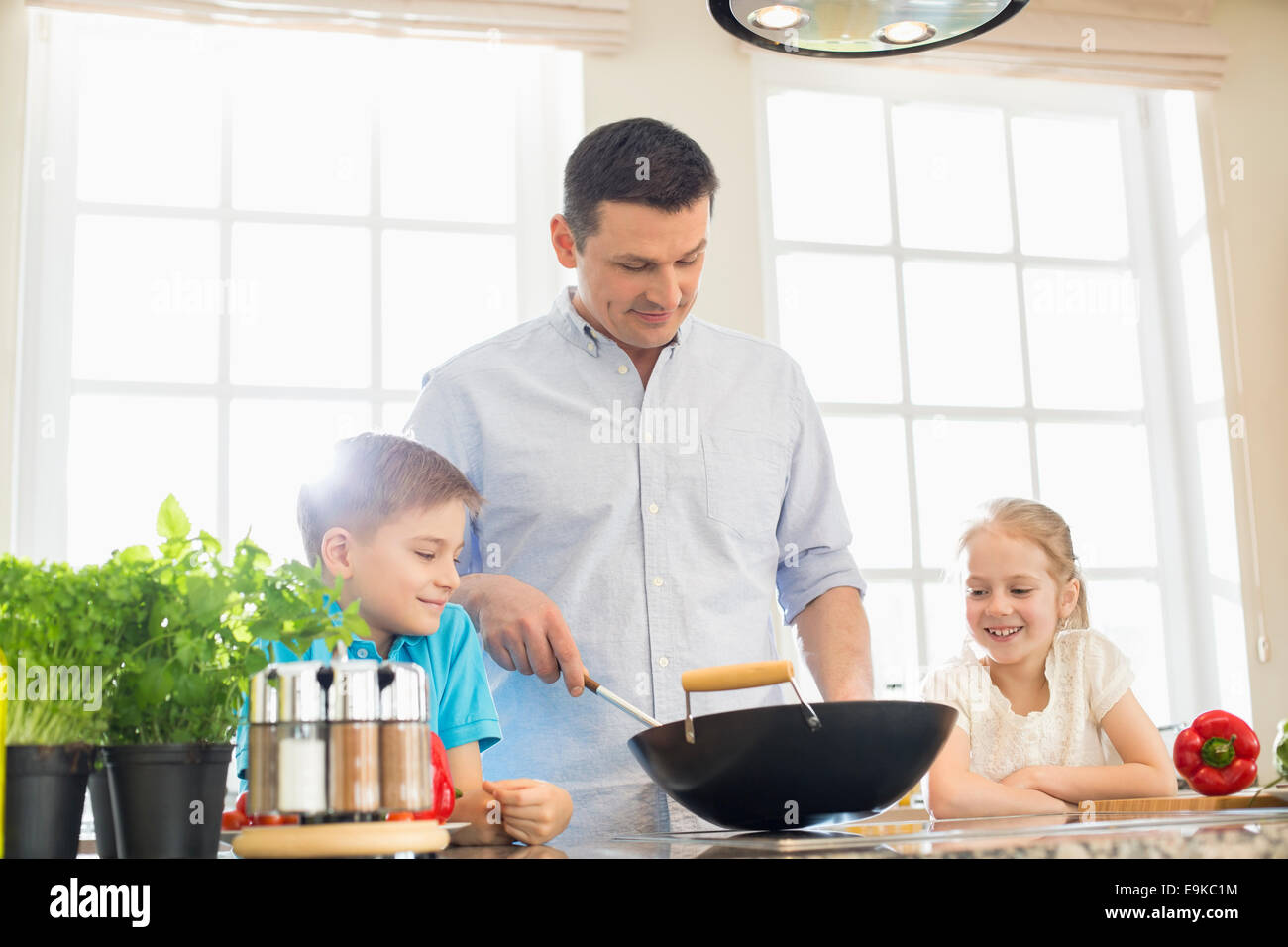 I bambini guardando il padre nella preparazione degli alimenti in cucina Foto Stock