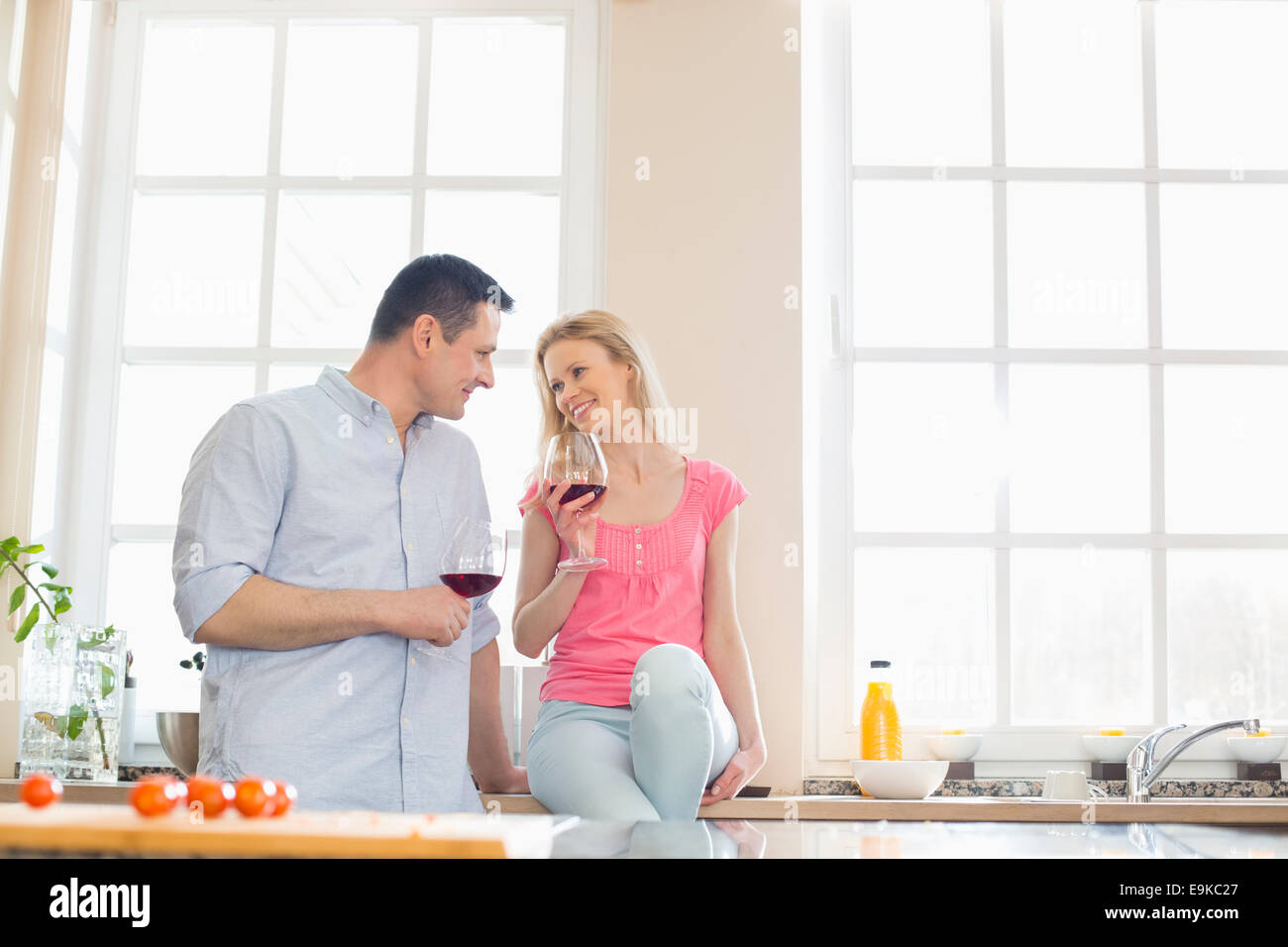 Coppia felice guardando ogni altro mentre si beve il vino rosso in cucina Foto Stock