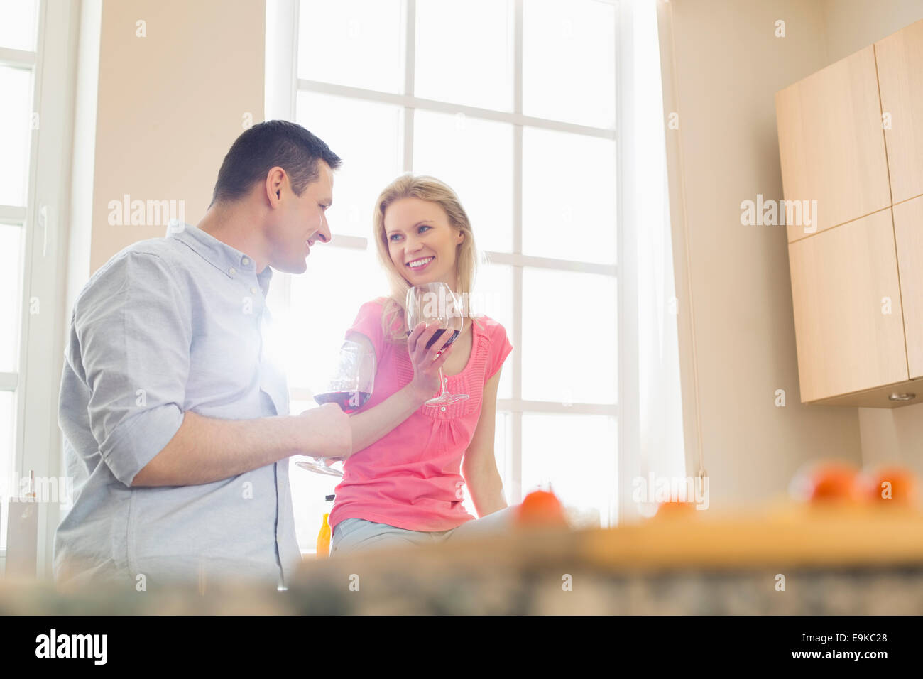 Coppia felice di bere il vino rosso in cucina Foto Stock