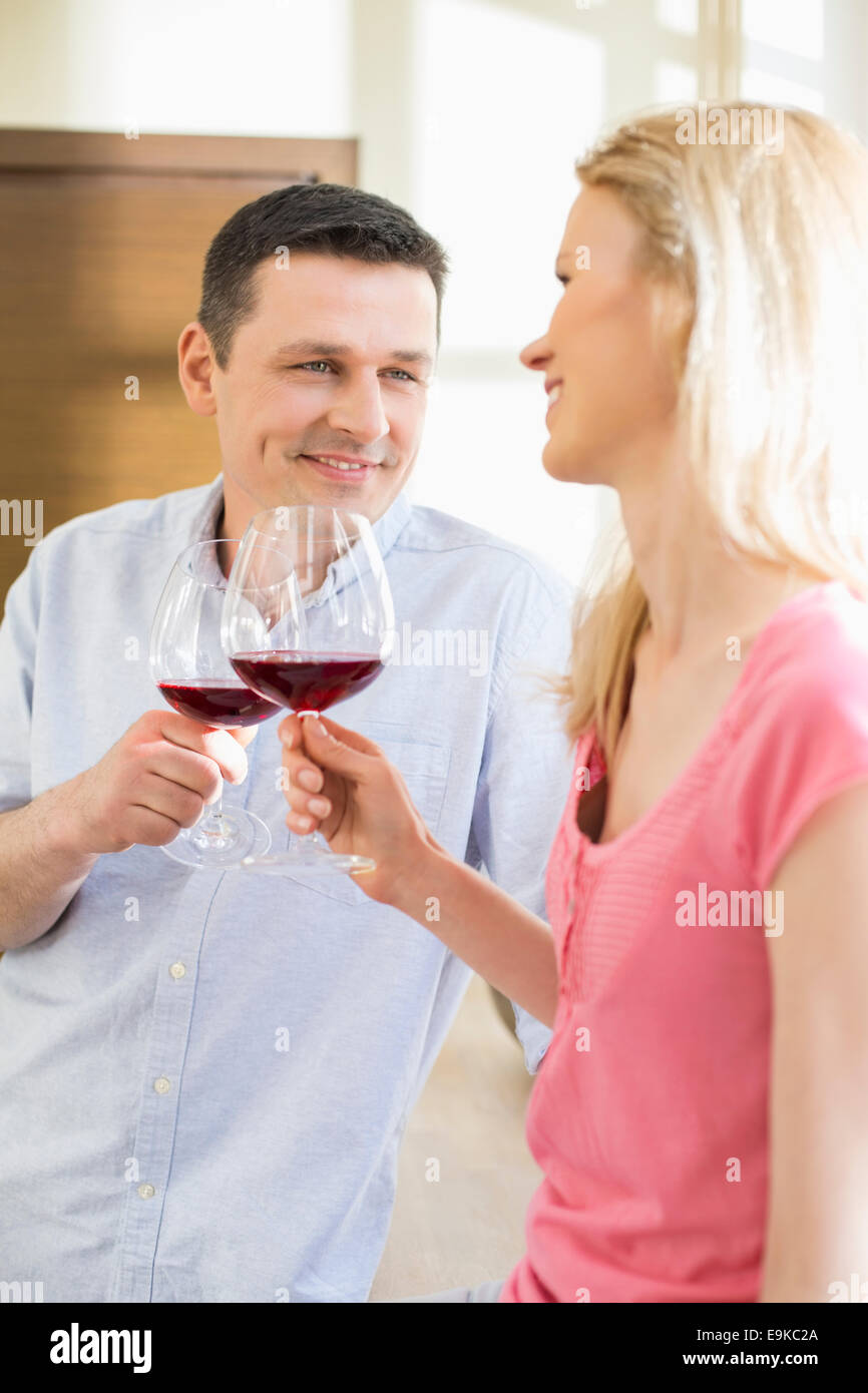 Felice coppia rosso di tostatura bicchieri di vino in cucina Foto Stock
