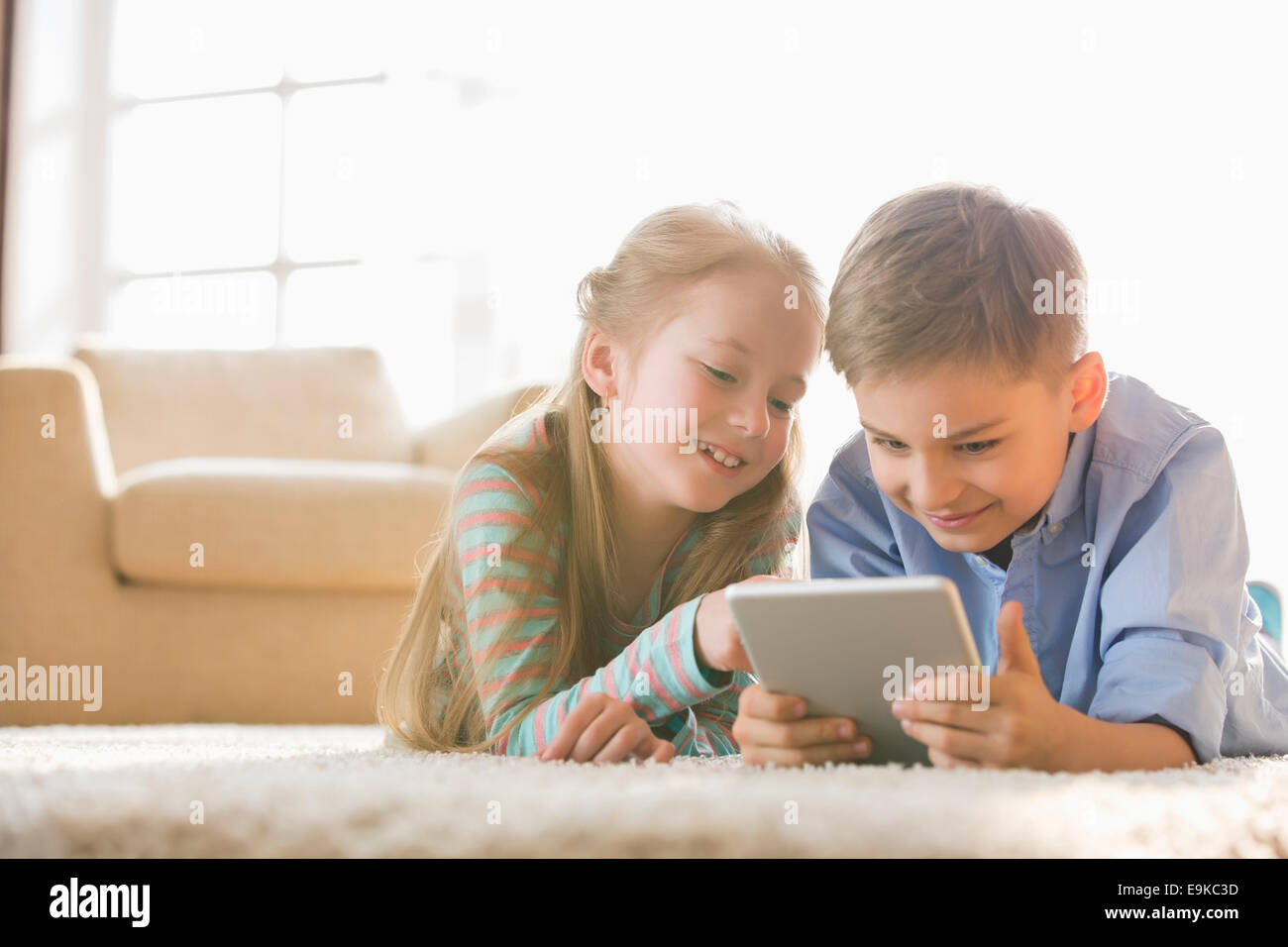 Fratello e Sorella con tavoletta digitale sul pavimento a casa Foto Stock