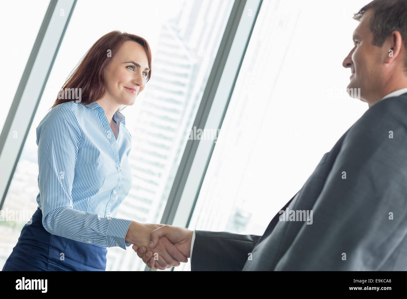 Vista laterale di uomini di affari che stringono le mani in office Foto Stock