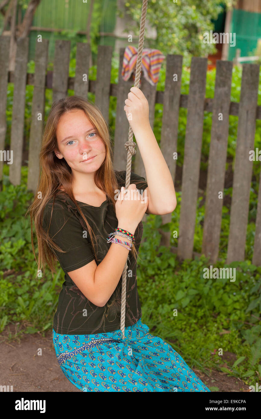 Teen girl basculante in una corda swing in campagna. Foto Stock