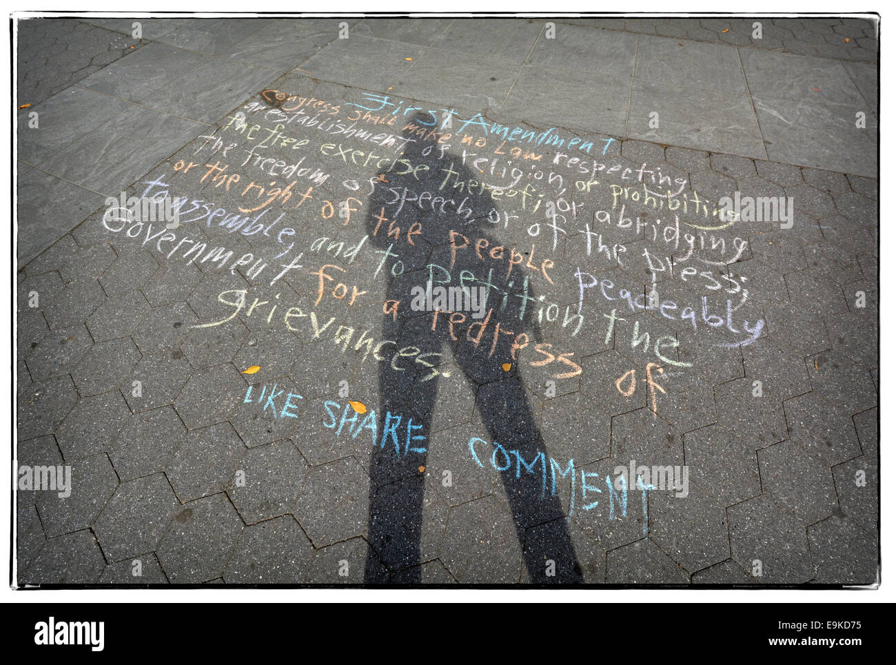 Un autoritratto di un fotografo la cui ombra si estende su di una matita versione del primo emendamento n. In Washington Square Park. Foto Stock