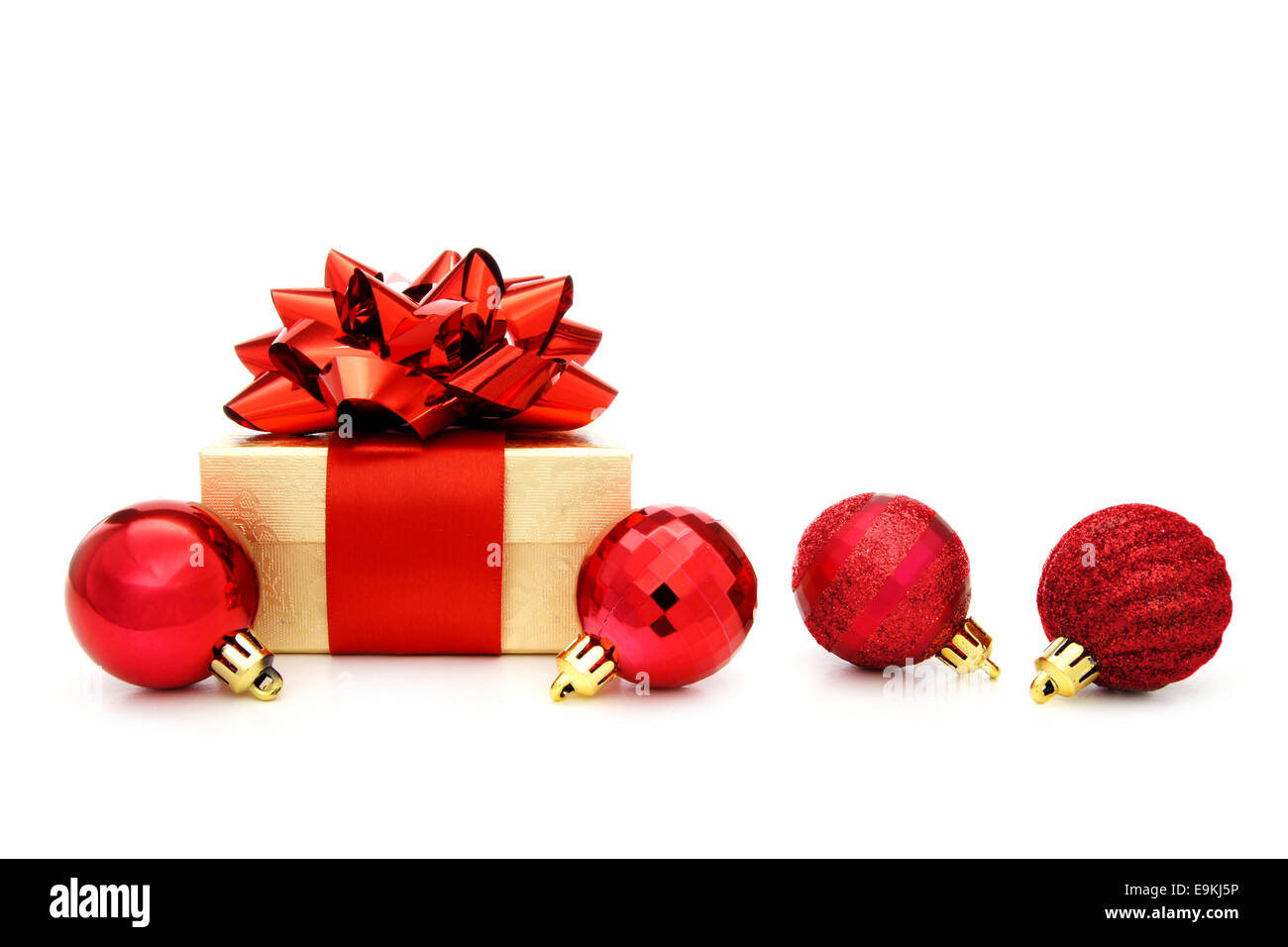 Oro regalo di Natale scatola con fiocco rosso e rosso ninnolo decorazioni su un bianco Foto Stock