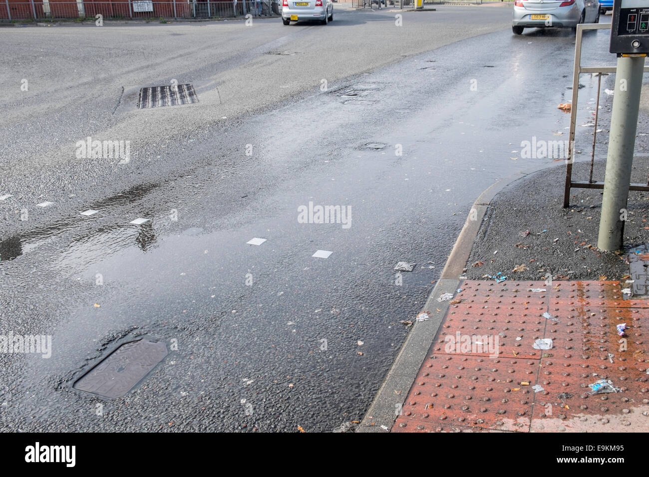 Perdita acqua sulla strada che è un problema ambientale con lo spreco di acqua causata da burst acqua principali. Foto Stock
