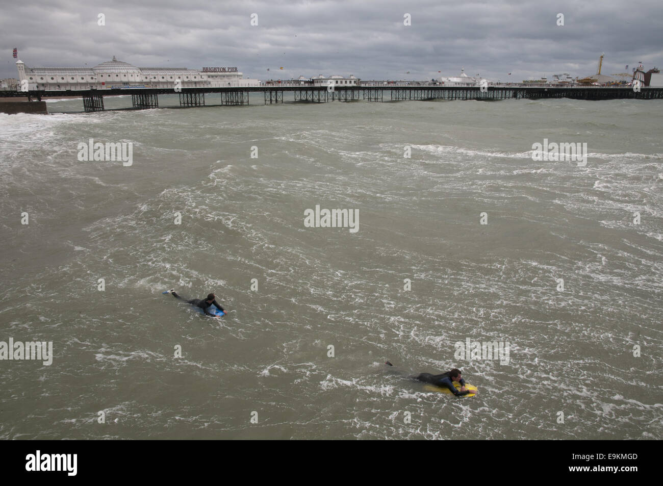 Due surfisti in freddo e ruvido acque fuori la spiaggia di Brighton, Inghilterra Foto Stock