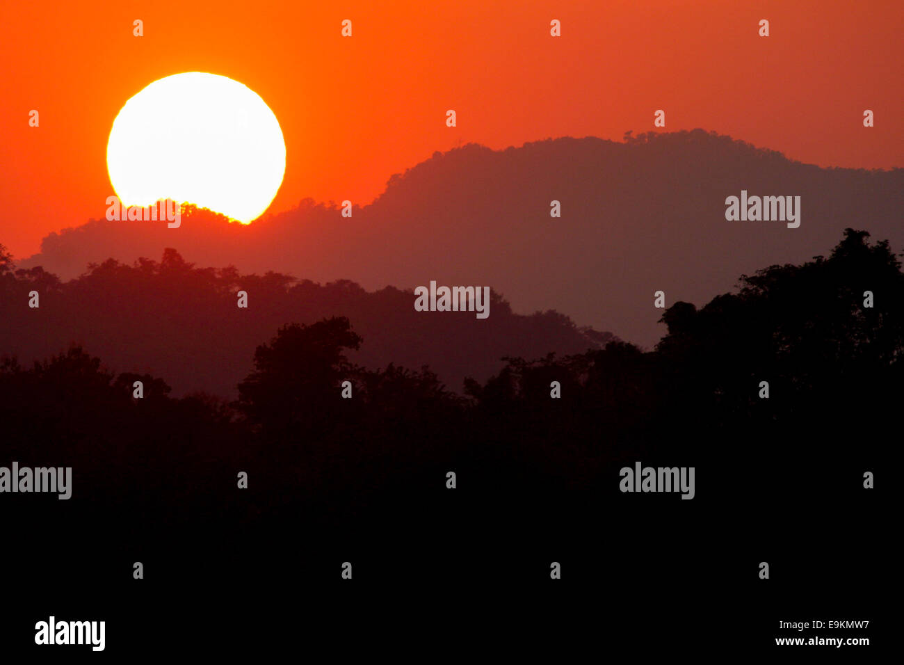 Il sole comincia a nascondersi dietro la densa, Laos jungle. Foto Stock