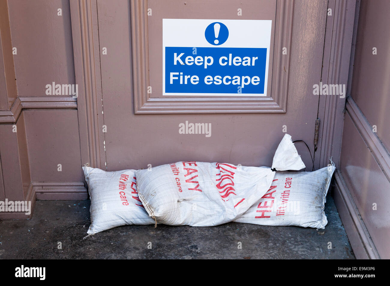 Sacchi di sabbia in appoggio contro un incendio porta fuga in preparazione contro le inondazioni. Foto Stock