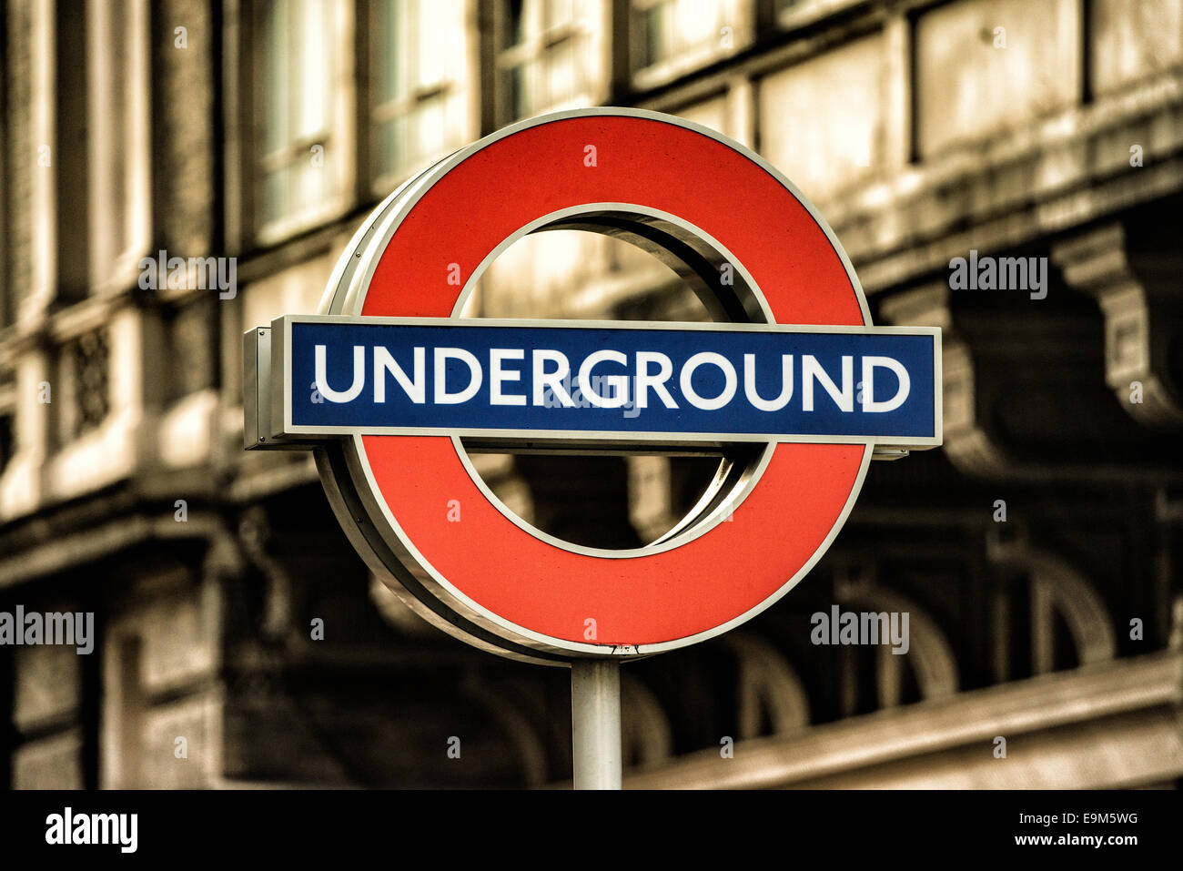 London Underground Roundel Sign London // LONDON, United Kingdom - l'iconico cartello della metropolitana di Londra, con un cerchio rosso e una barra blu, segna l'ingresso di una stazione della metropolitana. Conosciuto come la "rotonda", questo simbolo è un emblema ampiamente riconosciuto del sistema di trasporto pubblico di Londra. La metropolitana di Londra, comunemente nota come metropolitana, è una delle più antiche ed estese reti metropolitane del mondo, avendo aperto la sua prima linea nel 1863. Il caratteristico design rotondo è stato parte dell'identità visiva di Londra dal 1908, evolvendosi dai disegni precedenti per diventare il simbolo recogni Foto Stock