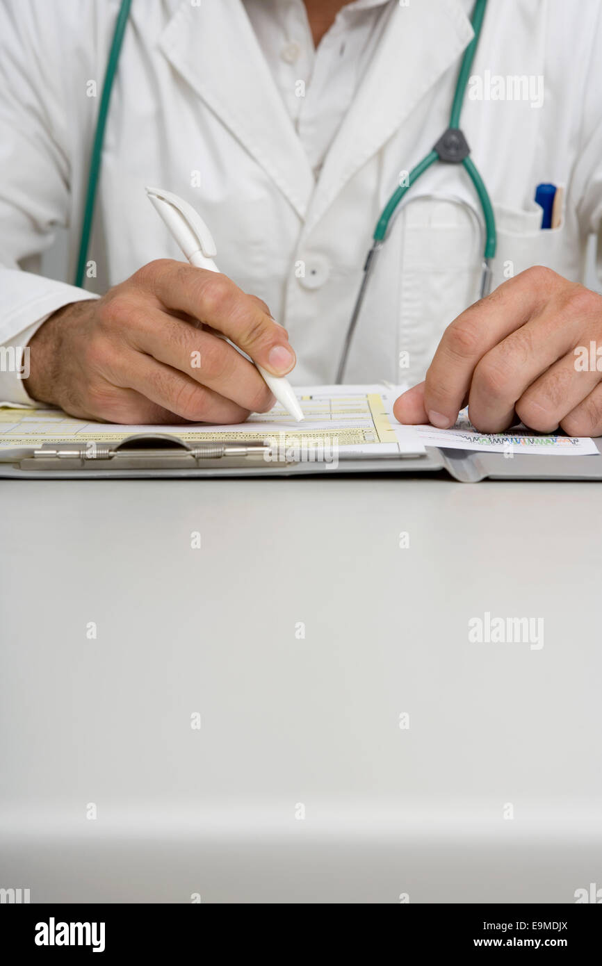 Close-up del medico con le mani in mano a scrivere a scrivania Foto Stock