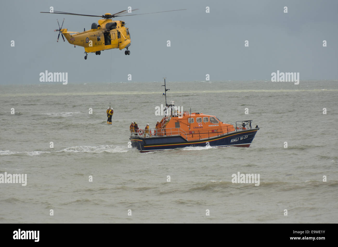 Un Royal Air Force Sea King elicottero compie un esercizio di formazione mediante la restituzione di due volontari RNLI a Eastbourne scialuppa di salvataggio. Foto Stock