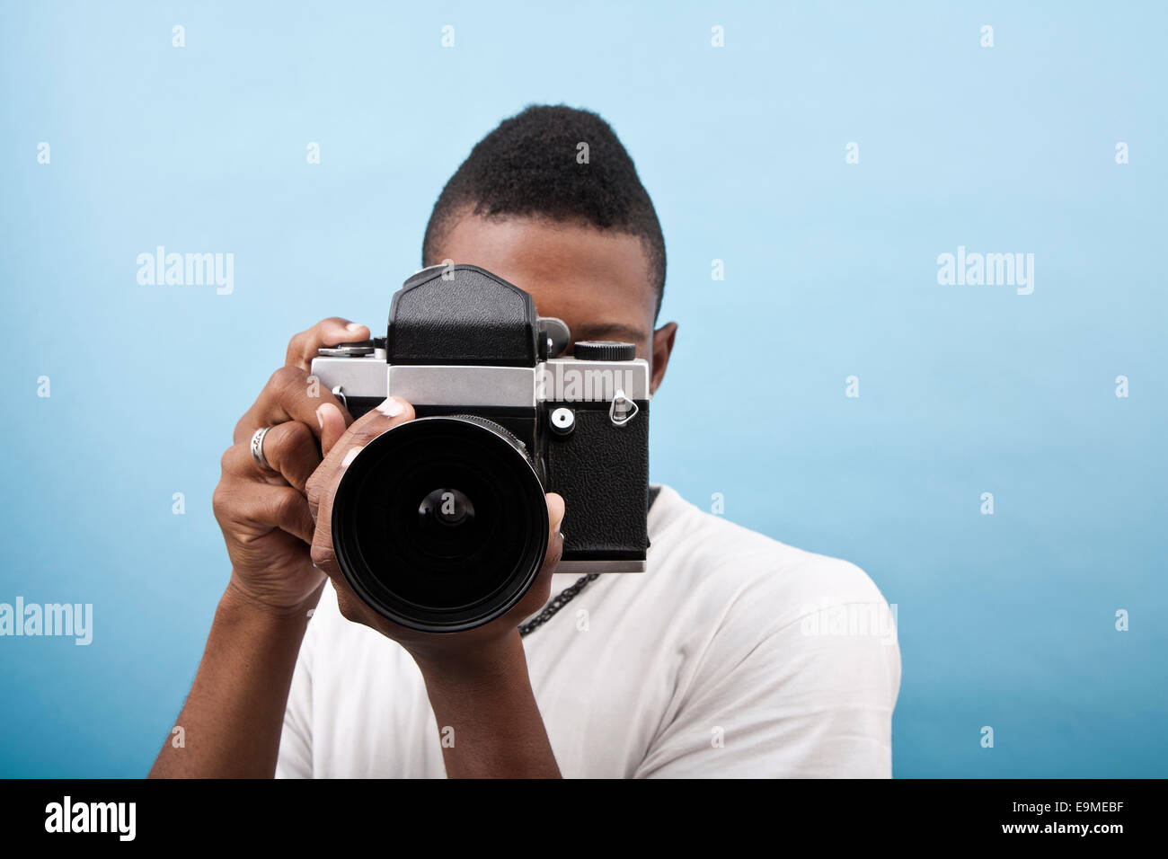Un giovane uomo nero utilizzando una vecchia telecamera Foto Stock