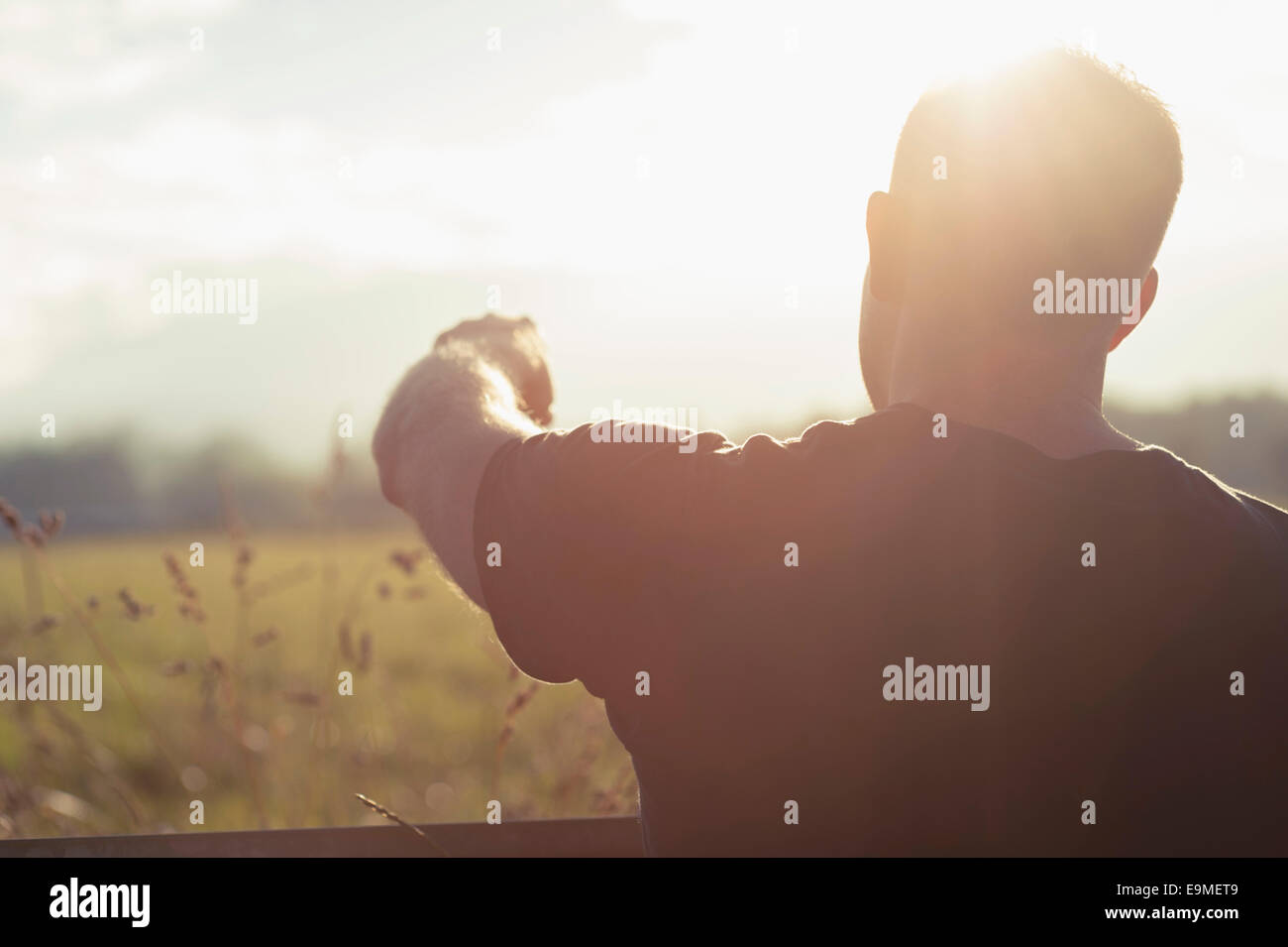 Vista posteriore dell'uomo puntando al campo sulla giornata di sole Foto Stock