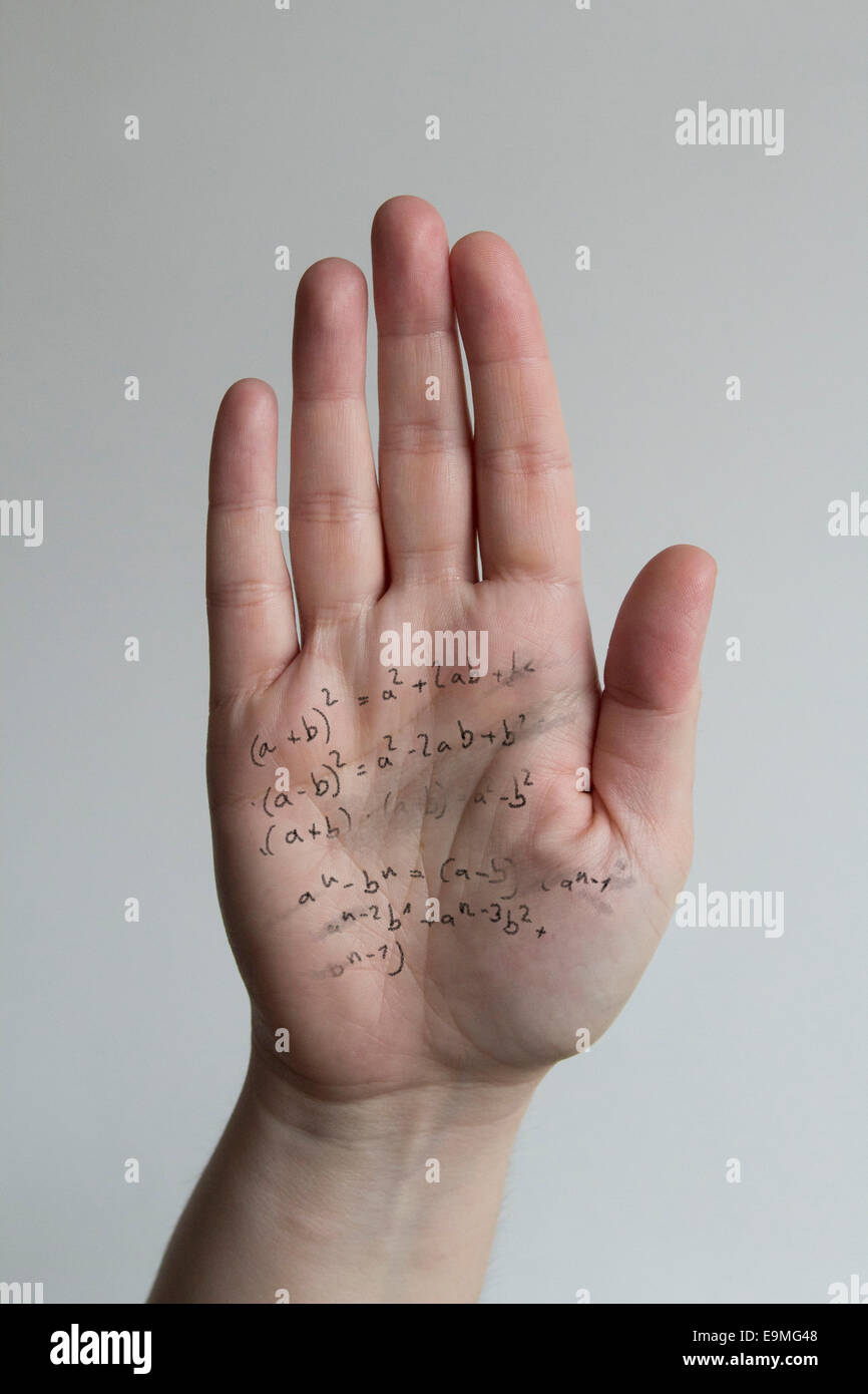 Close-up di formule scritte sulla mano d'uomo contro uno sfondo grigio Foto Stock