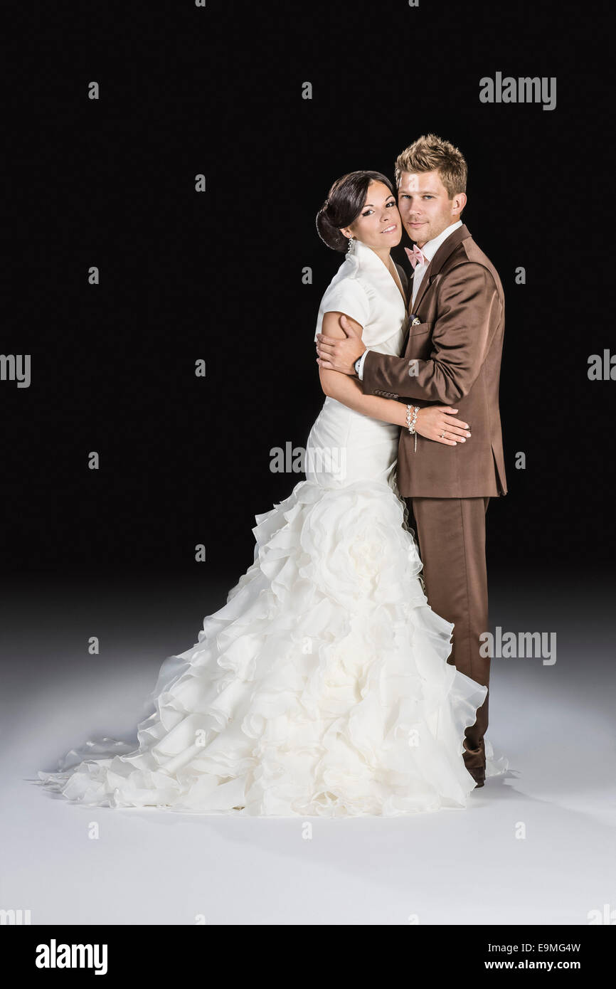Lunghezza piena vista laterale della sposa e lo sposo in piedi su sfondo nero Foto Stock
