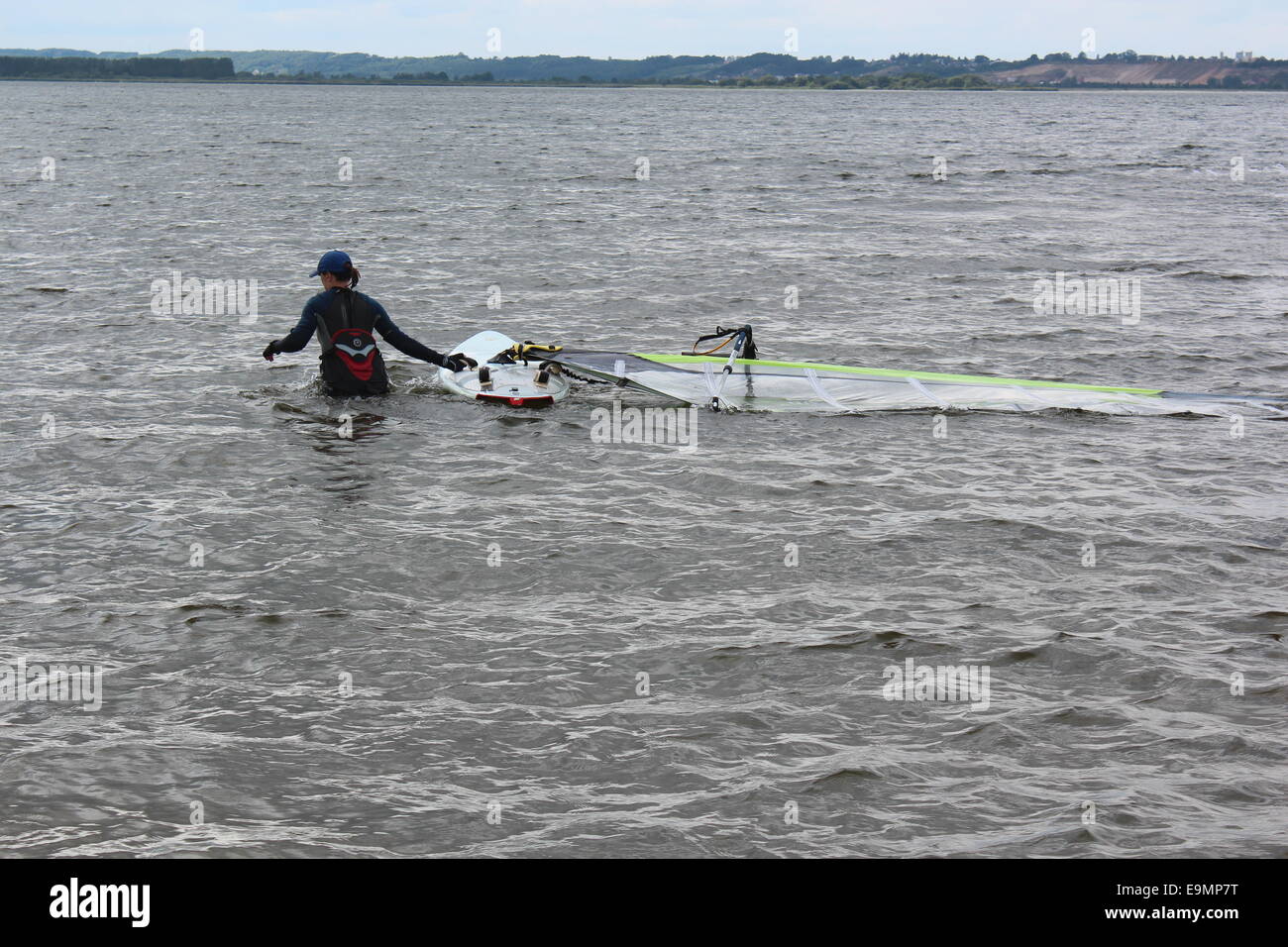 Polonia, Rewa 17 Agosto 2014: Principiante windsurfista femmina impara a windsurf. Essa si erge in acqua e tira la sua tavola da surf. Foto Stock