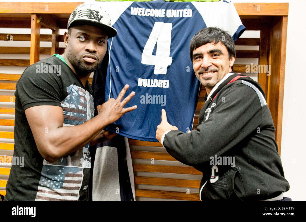 Potsdam, Germania. 26 ott 2014. Hassan dalla Macedonia, pullman di Welcome-United-Nulldrei e portiere Deuton posano con il jersey sponsorizzata negli spogliatoi in Karl-Liebknecht stadion di Potsdam, Germania, 26 ottobre 2014. Come dei rifugiati recentemente formano una propria squadra di calcio a SV Babelsberg 03. Foto: Oliver Mehlis/dpa/Alamy Live News Foto Stock