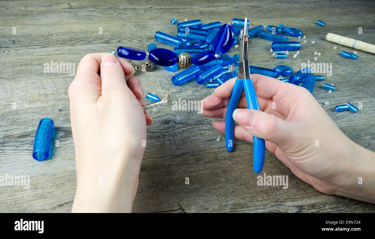 Donna con le mani in mano facendo una collana di perle di vetro Foto Stock