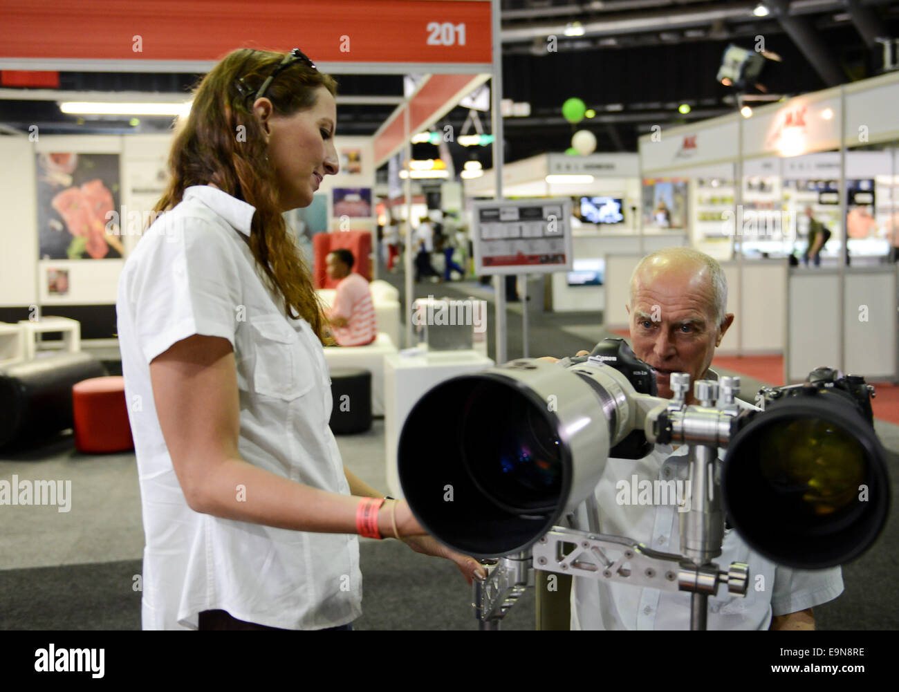 Johannesburg, Sud Africa. 30 ott 2014. Un espositore (L) mostra un auto-progettato dispositivo che due telecamere possono essere dotate di un visitatore durante la foto & Film Expo che si terrà a Johannesburg, in Sud Africa il Ott 30, 2014. Foto & Film Expo, che è la più grande esposizione fotografica in Africa, calci fuori qui il giovedì. Secondo l'organizzatore, la manifestazione annuale riunirà oltre 20.000 industria creative e oltre 400 marchi fotografici per 4 giorni questo anno e oltre 100 presentazioni e dimostrazioni sono pianificate per essere offerto. © Zhai Jianlan/Xinhua/Alamy Live News Foto Stock