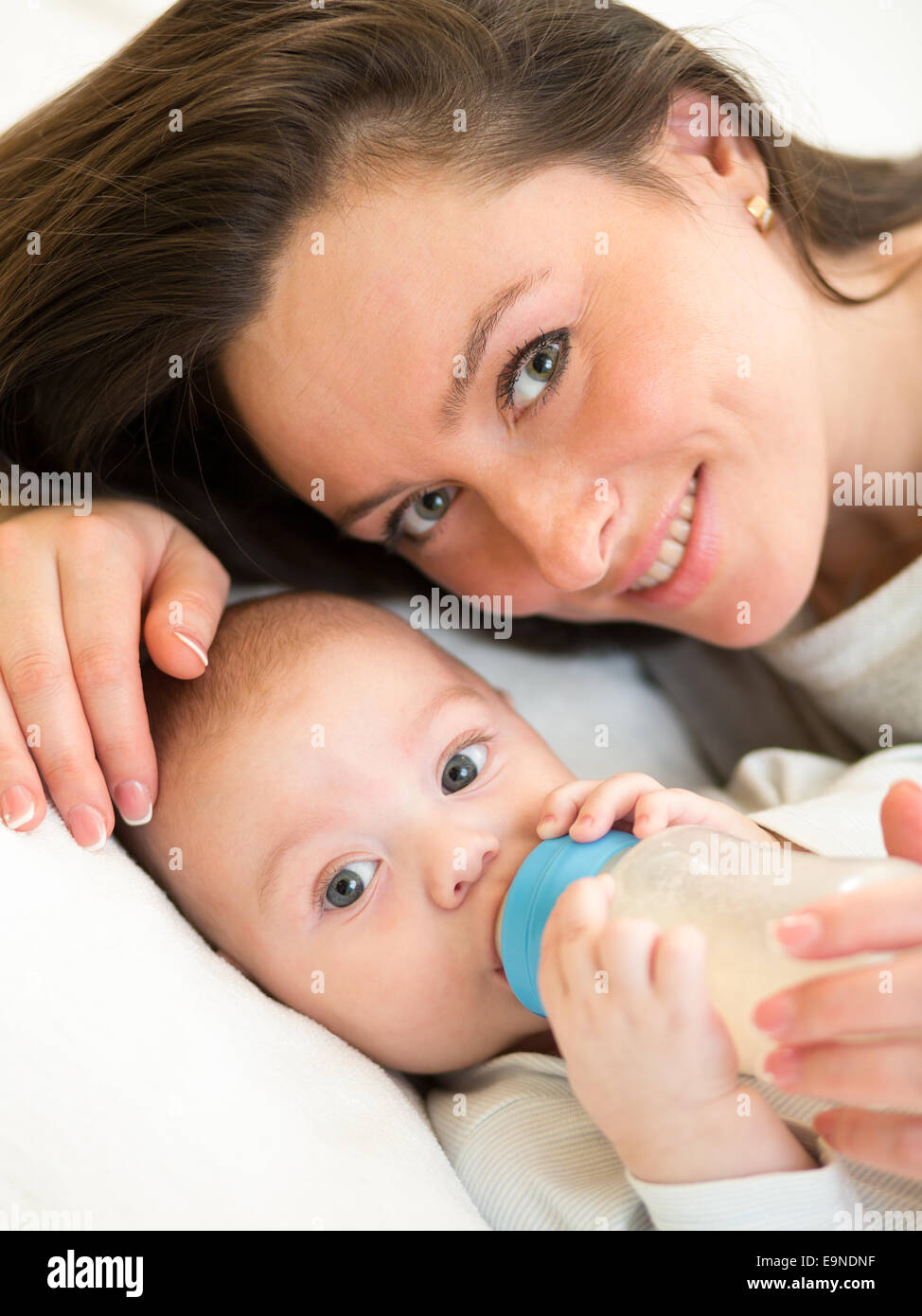 Alimentazione madre kid ragazzo con una bottiglia di latte a casa Foto Stock