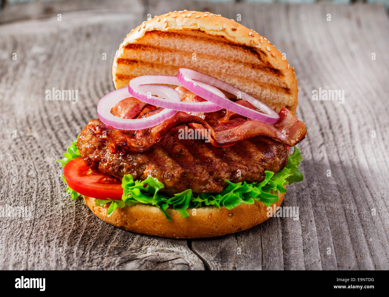 Hamburger con pancetta e carne alla griglia su una superficie in legno Foto Stock