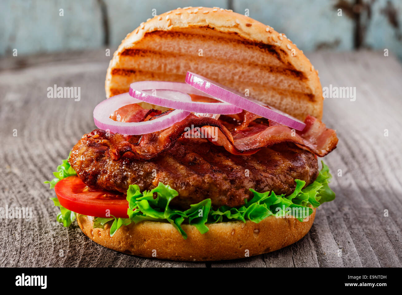 Hamburger con pancetta e carne alla griglia su una superficie in legno Foto Stock