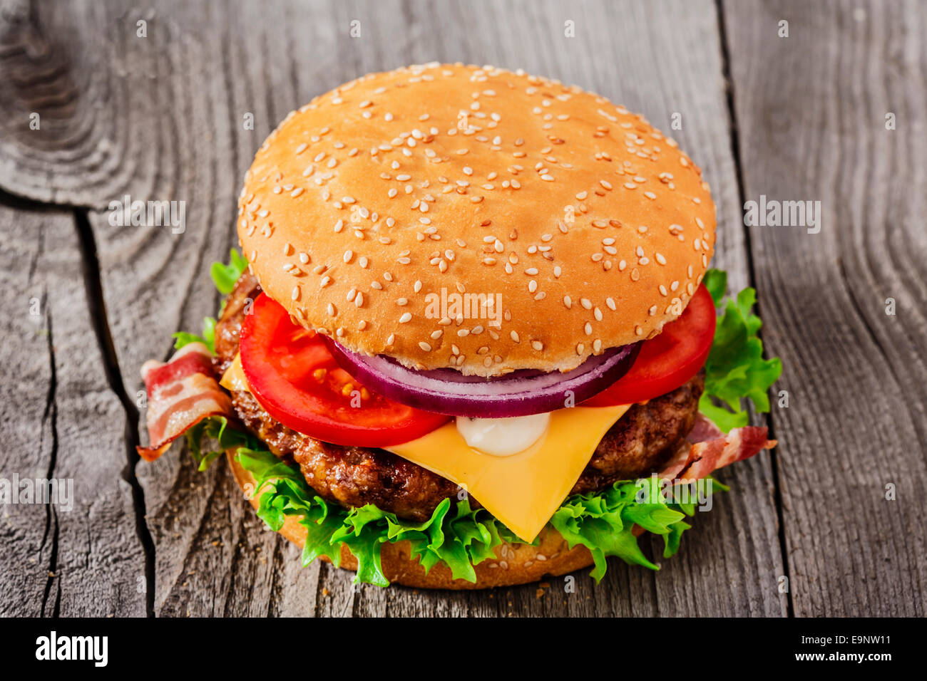 Hamburger con grigliate di carne e di formaggio e pancetta affumicata su una superficie in legno Foto Stock