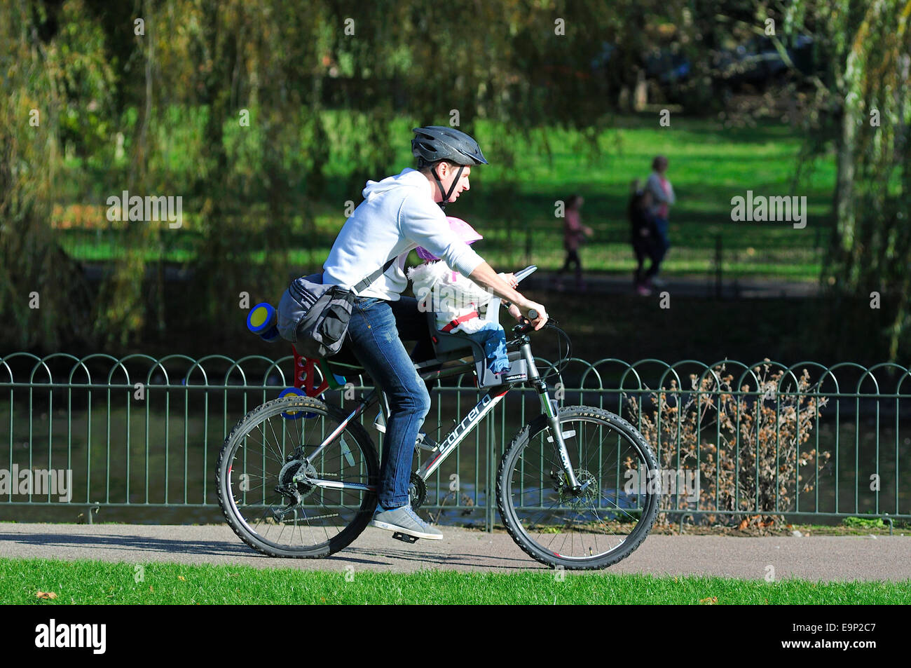 Padre Bicicletta Equitazione con bambino piccolo nel Parco Wardown, Luton, Bedfordshire Foto Stock