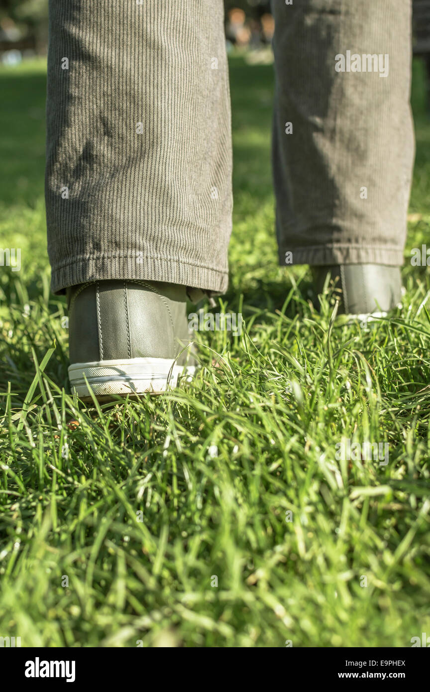 Persona che cammina sul prato verde. Immagine con profondità di campo ridotta. Foto Stock