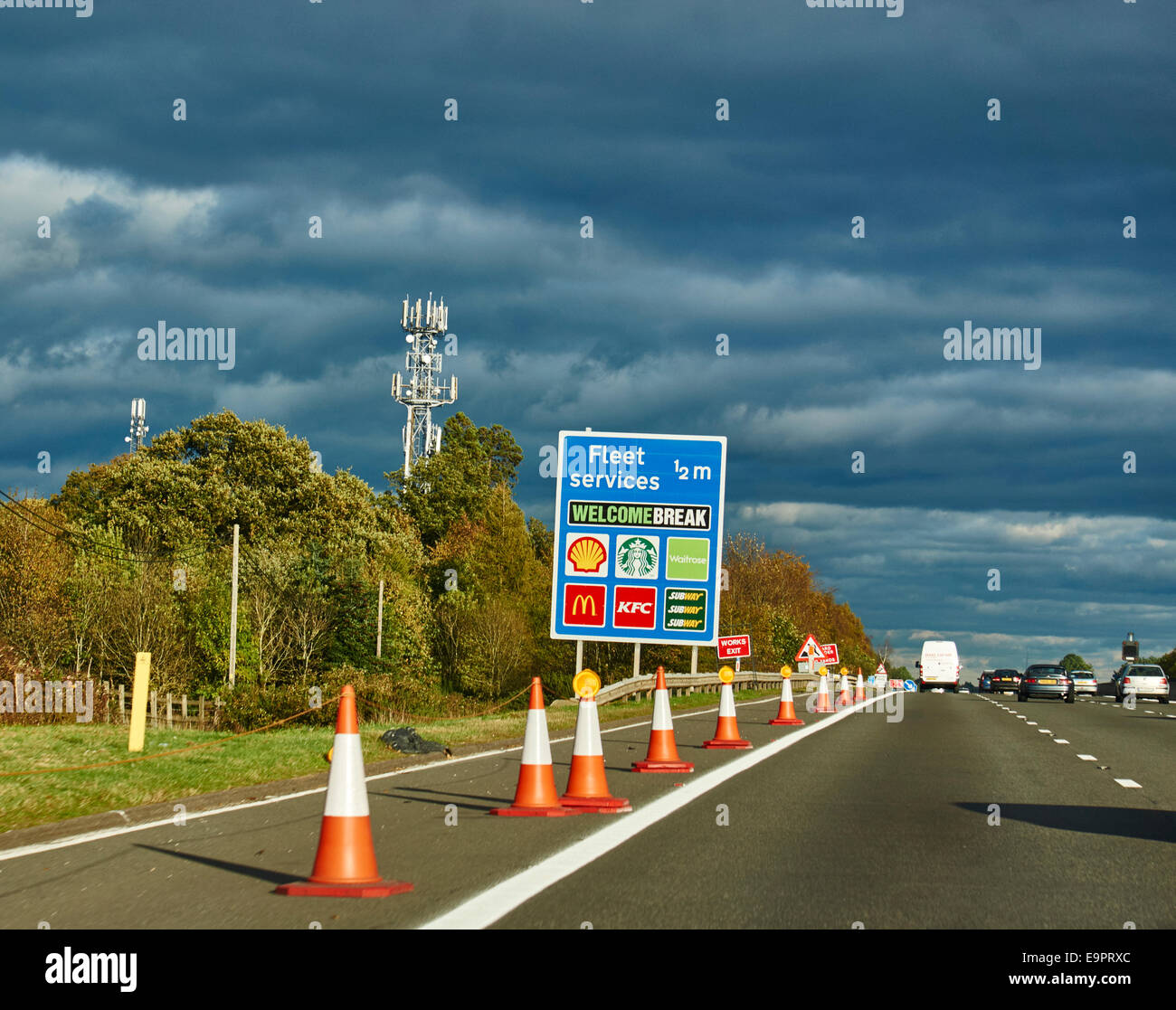 Servizi di flotta uscire da firmare e l'autostrada M4 in Hampshire, nella calda serata sole. Coni di rivestimento del disco spalla. Inghilterra, Regno Unito. Foto Stock