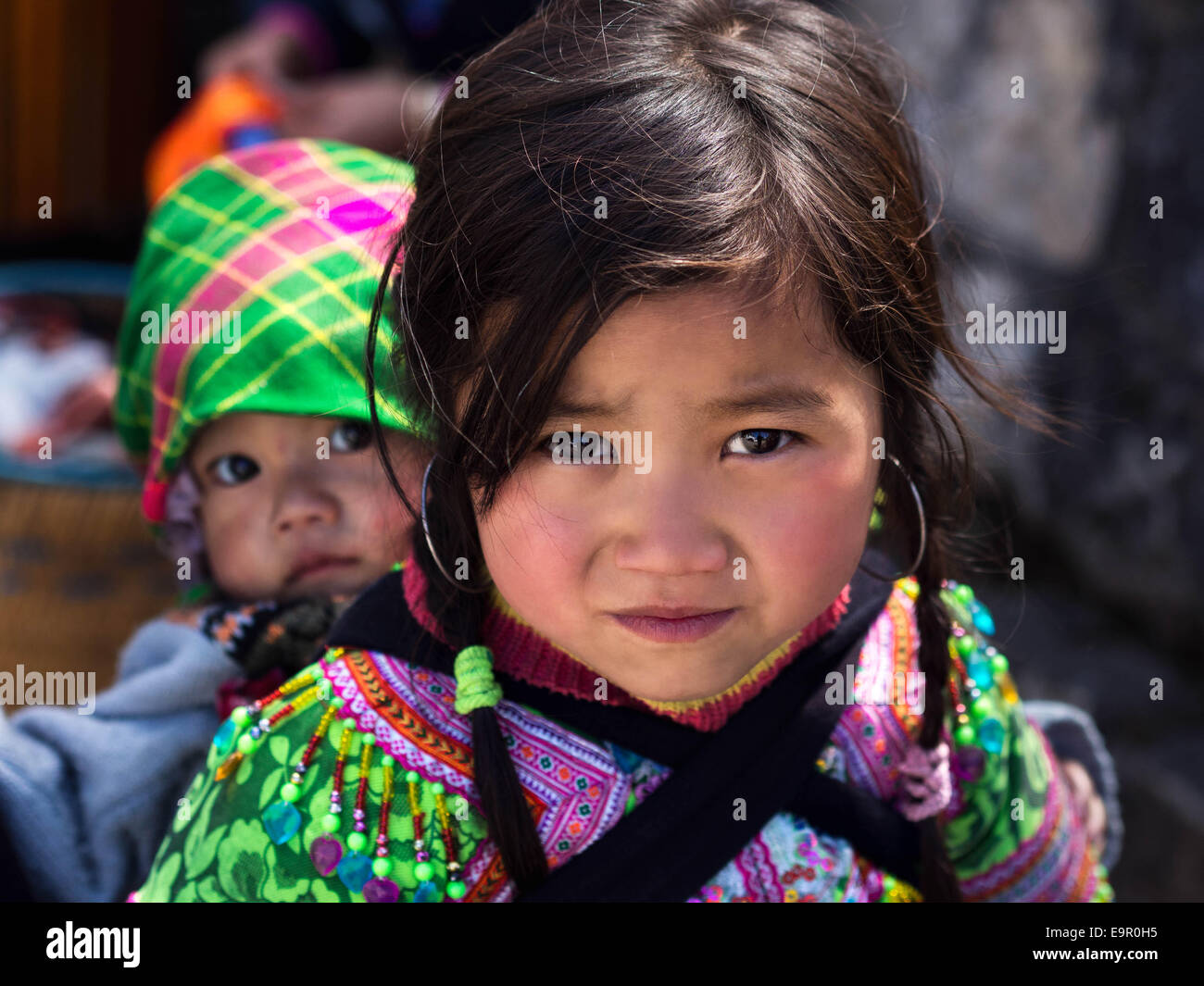Non identificato ragazza Hmong trasporto bambini e indossando costumi tradizionali di Sapa, Lao Cai Provincia, Vietnam. Foto Stock