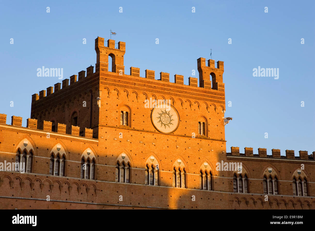 Siena, Toscana, Italia. La facciata del Palazzo Pubblico (Palazzo Comunale) illuminato dal sole al tramonto, Piazza del Campo. Foto Stock