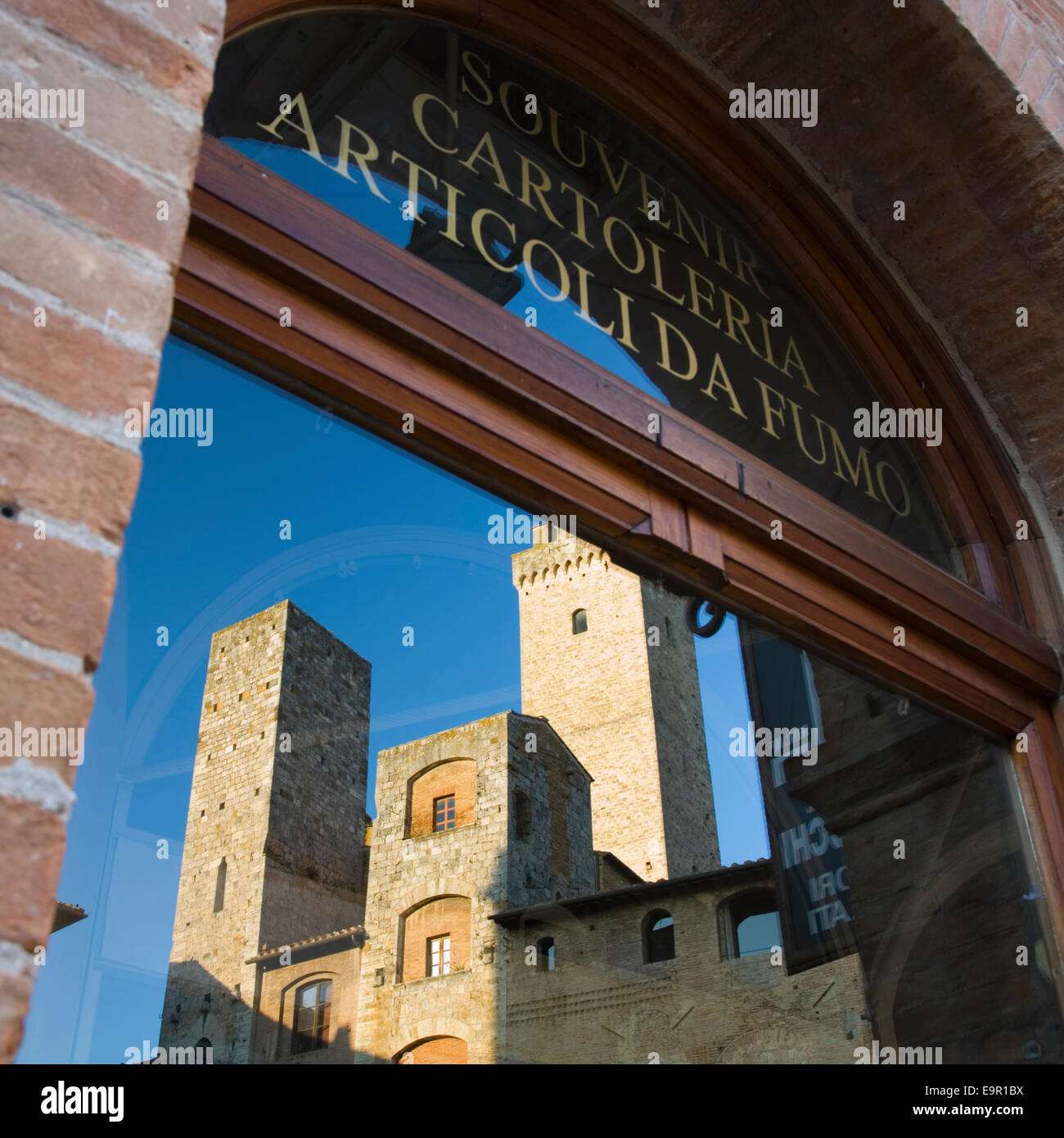 San Gimignano, Toscana, Italia. Torri medievali riflessa nella vetrina di un negozio di souvenir in Piazza della Cisterna. Foto Stock