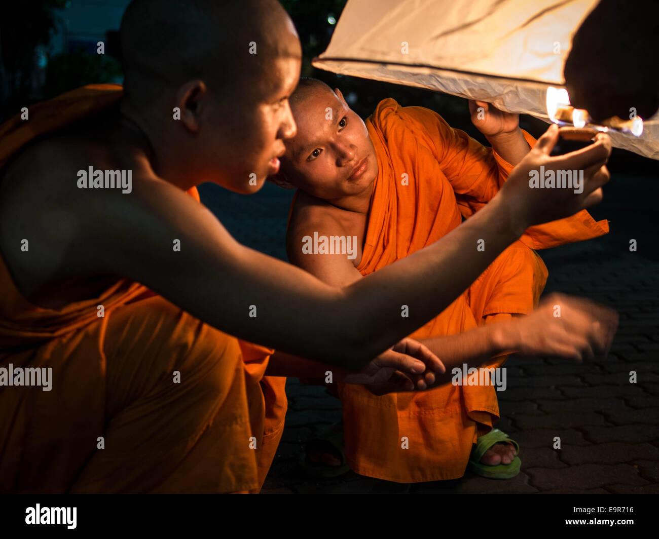 Due arancio-derubato i monaci buddisti illuminazione di una carta di riso mongolfiera presso il Loy Krathong festival in Chiang Mai, Thailandia. Foto Stock