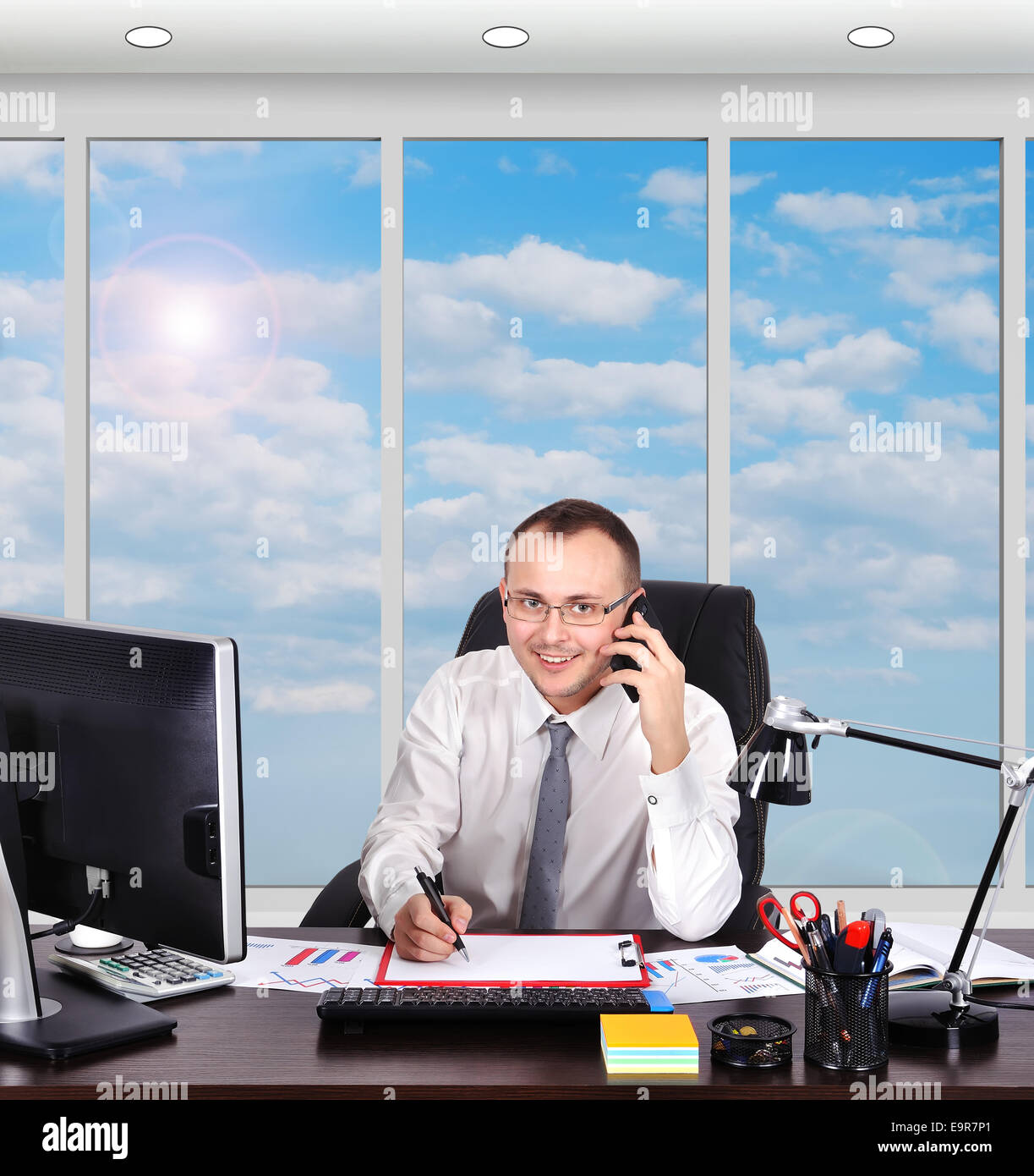 Giovane imprenditore seduto in ufficio con il telefono Foto Stock