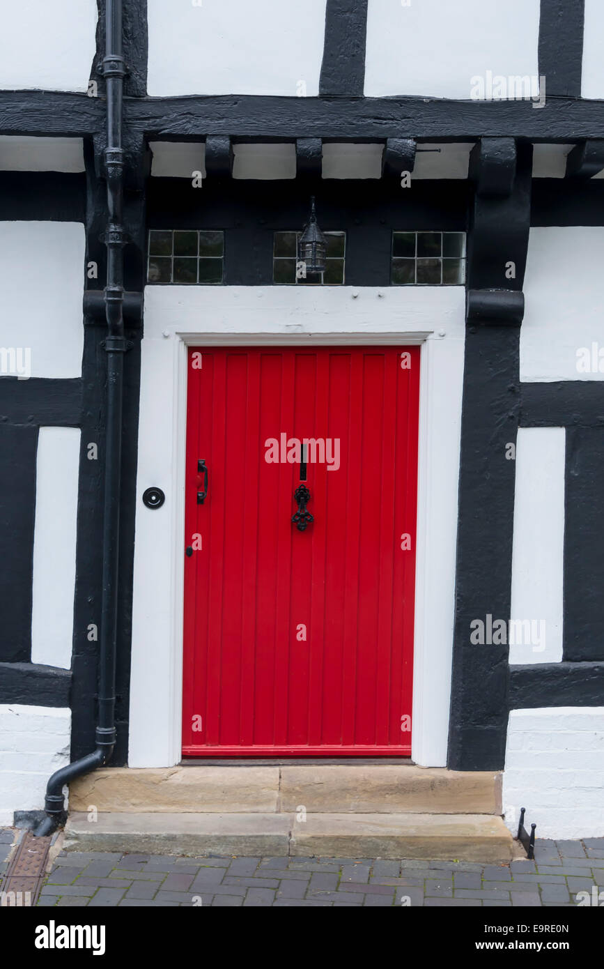 Rosso porta anteriore in un inglese tradizionale con la struttura di legno Tudor House Foto Stock