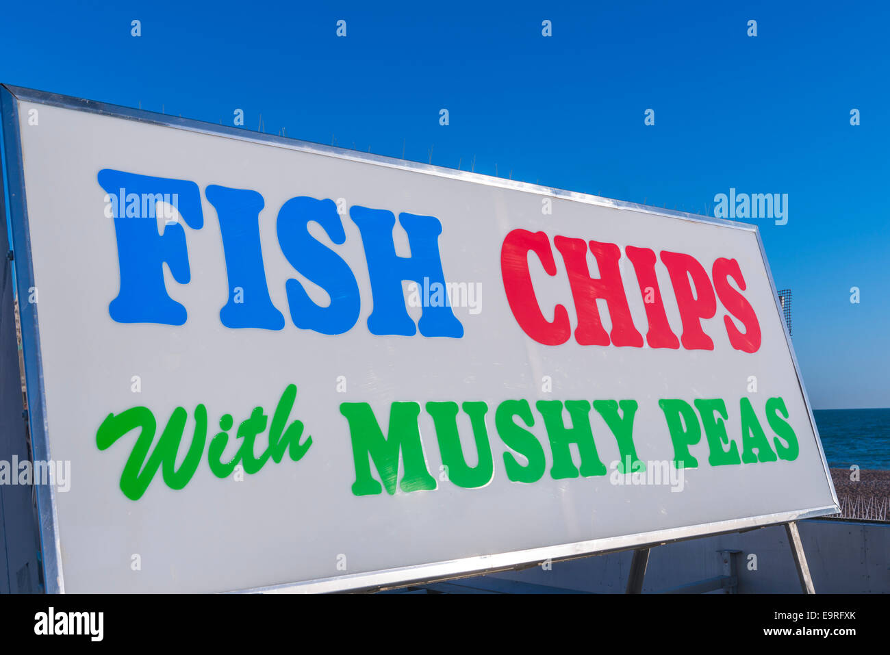 Un colorato e bold segno pubblicità pesce, patatine con fiacco piselli sul lungomare di Brighton Foto Stock